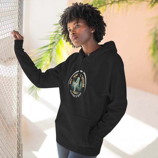 A black pullover hoodie with a circular graphic on the chest that reads 'Grit. Heart. Gratitude. Sophie's Way' around a globe design around a taekwondo tot doing a side kick. The hoodie features a drawstring hood, long sleeves, and a front kangaroo pocket.