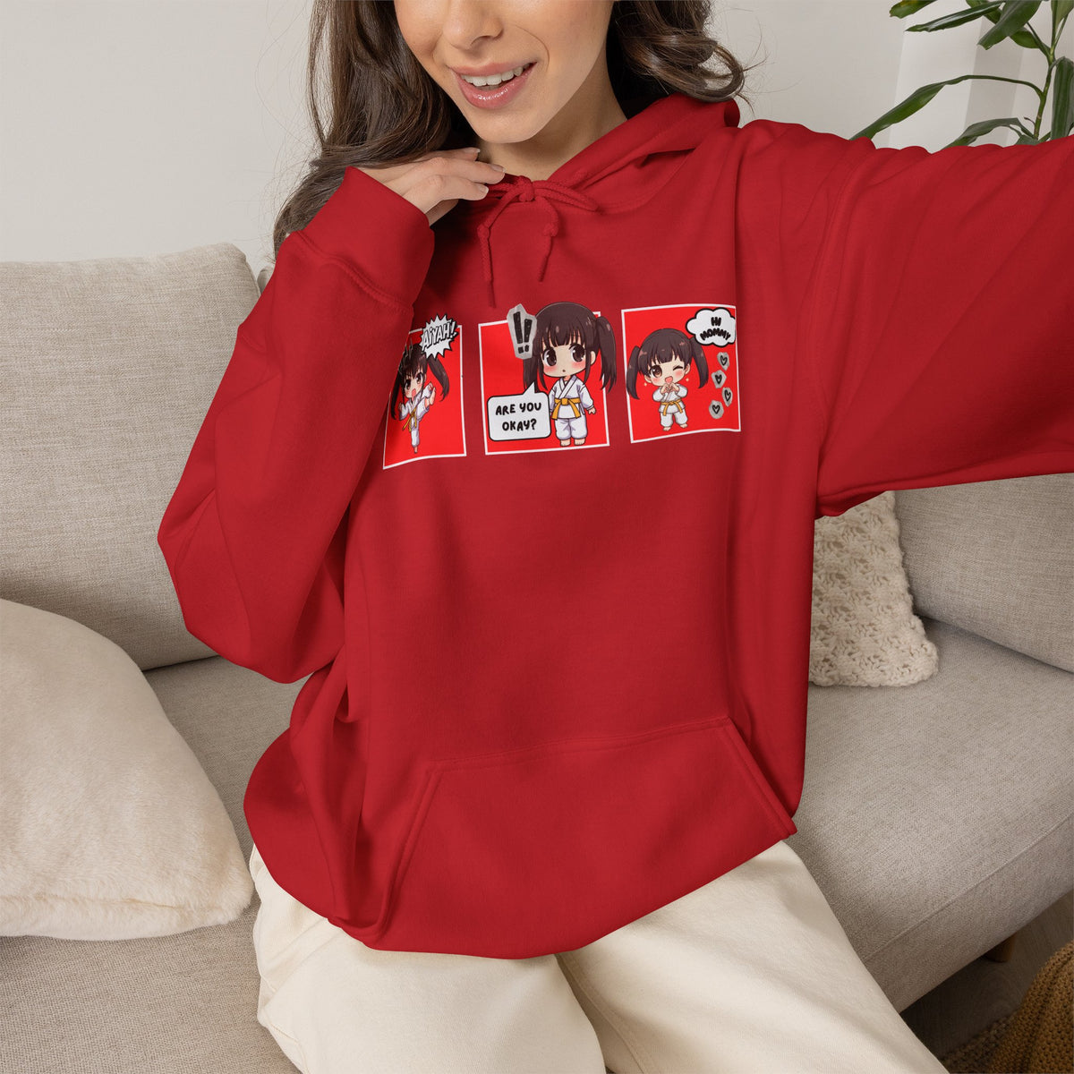 A red pullover hoodie with a red and multicolor anime-style graphic print on the chest of a taekwondo girl saying 'Aiyah!' then 'Are you okay?', and then 'Hi Mommy.'
