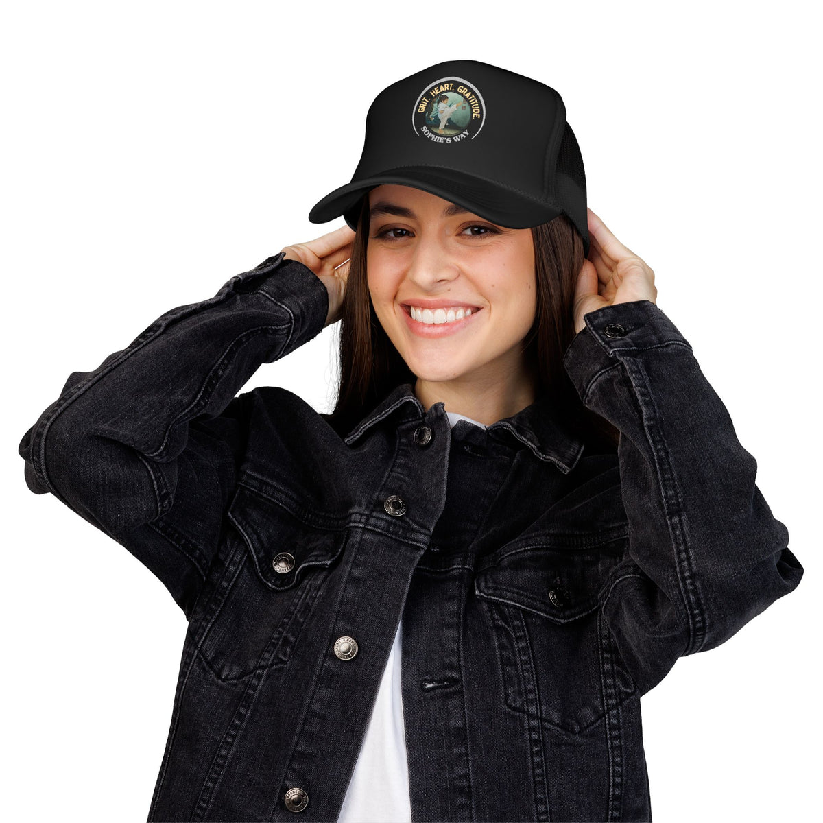 A black trucker hat with a circular graphic on the front panel. The graphic features a border with the words 'Grit. Heart. Gratitude. Sophie's Way' and a taekwondo tot doing a side kick in the center.
