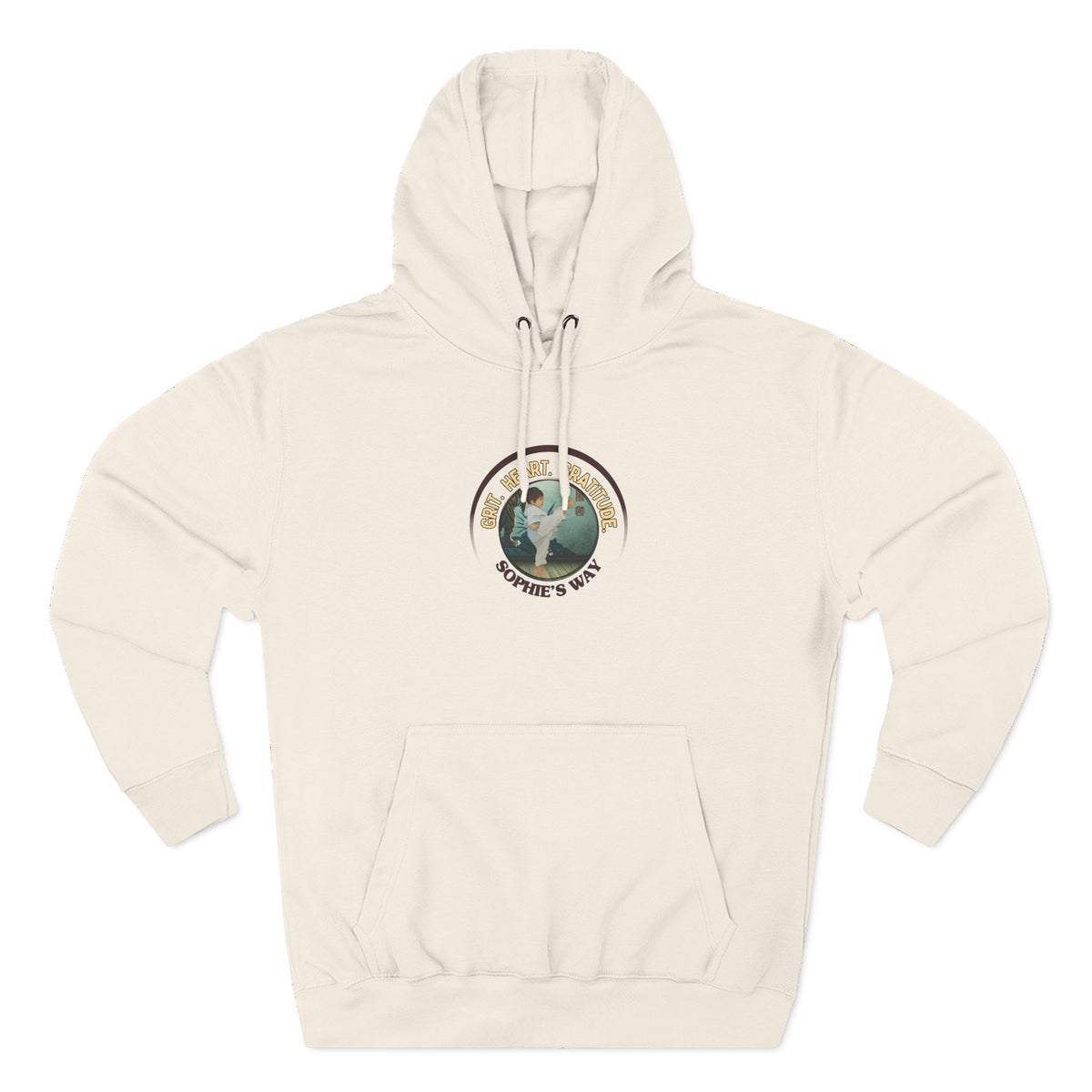A sandshell pullover hoodie with a circular graphic on the chest that reads 'Grit. Heart. Gratitude. Sophie's Way' around a globe design around a taekwondo tot doing a side kick. The hoodie features a drawstring hood, long sleeves, and a front kangaroo pocket.