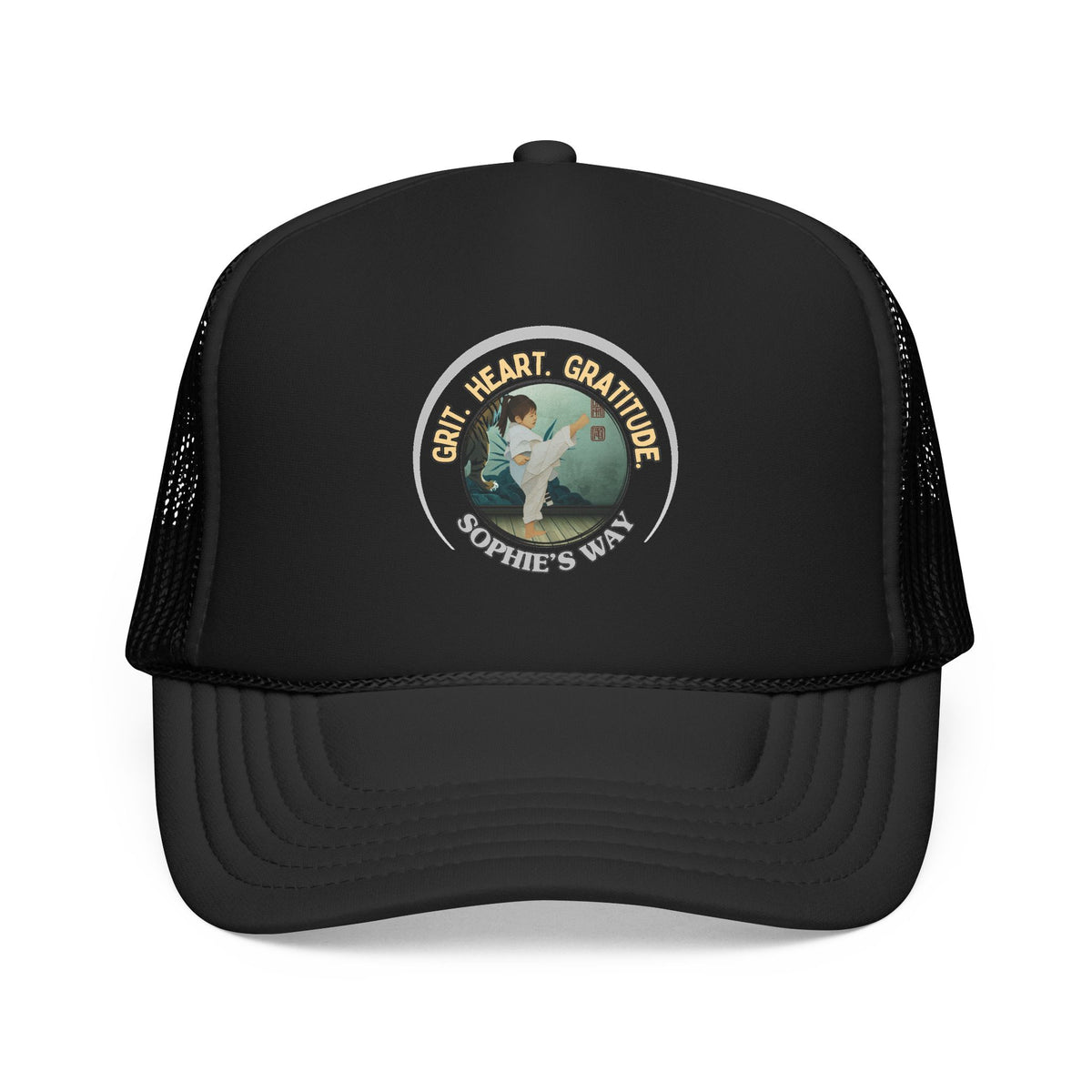 A black trucker hat with a circular graphic on the front panel. The graphic features a border with the words 'Grit. Heart. Gratitude. Sophie's Way' and a taekwondo tot doing a side kick in the center.