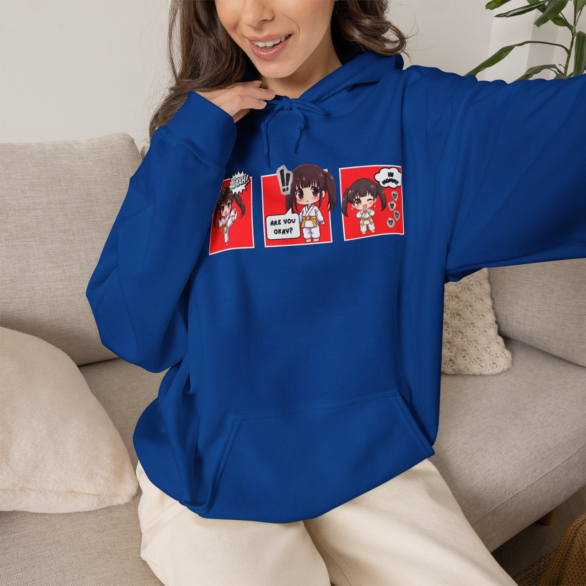 A royal blue pullover hoodie with a red and multicolor anime-style graphic print on the chest of a taekwondo girl saying 'Aiyah!' then 'Are you okay?', and then 'Hi Mommy.'