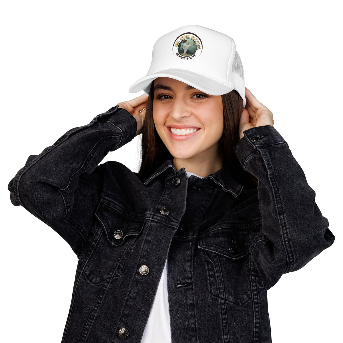 A white trucker hat with a circular graphic on the front panel. The graphic features a border with the words 'Grit. Heart. Gratitude. Sophie's Way' and a taekwondo tot doing a side kick in the center.